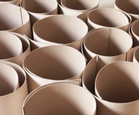 A DSLR photo of a group of corrugated cardboard rolls standing side by side. The high angle view shows the rounded shapes of the top of the rolls. The light from the side gives shape and texture to the cardboard rolls.