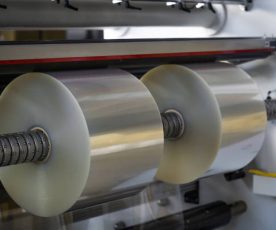 Transparent Film Rollers For Printing Self Adhesive Label On Shaft Cutting And Rewinding Reels Machine. Close-up
