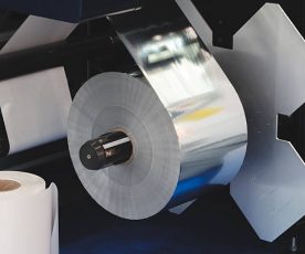 roll of plastic polyethylene film is cut by a food packaging machine. Industrial concept background.